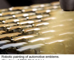 A robot applies paint to automotive emblems (due to SRG worldwide Inc.)
