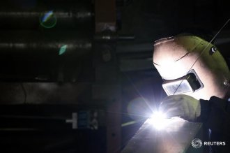 an employee welds iron at his steel item shop in Seoul