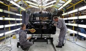 Workers making a black colored taxi inside factory regarding the London Taxi business factory.